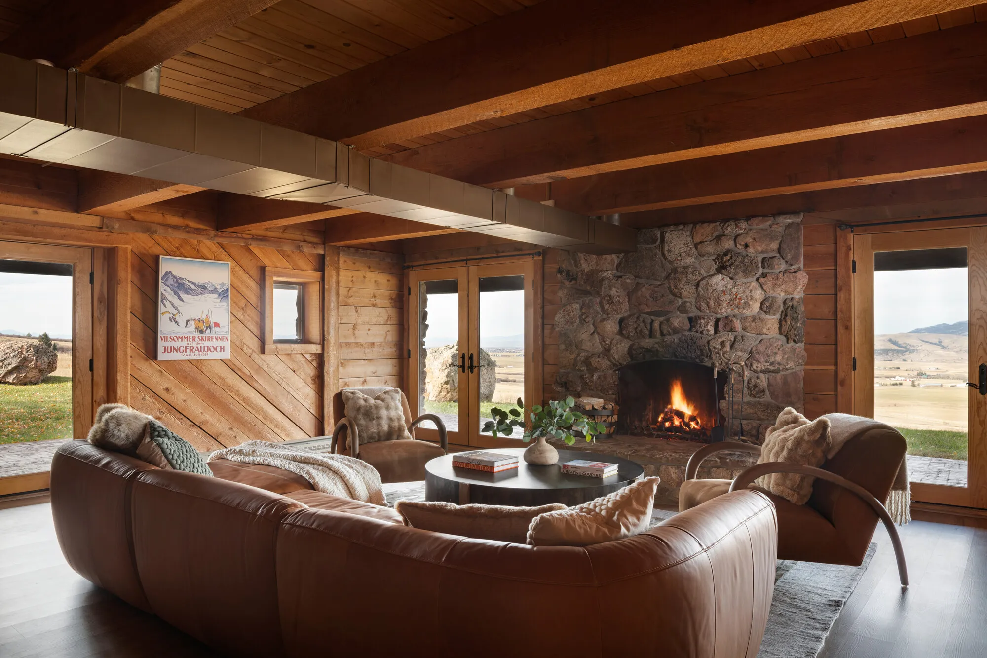 The lower level's second living room — stone fireplace, mountain light.