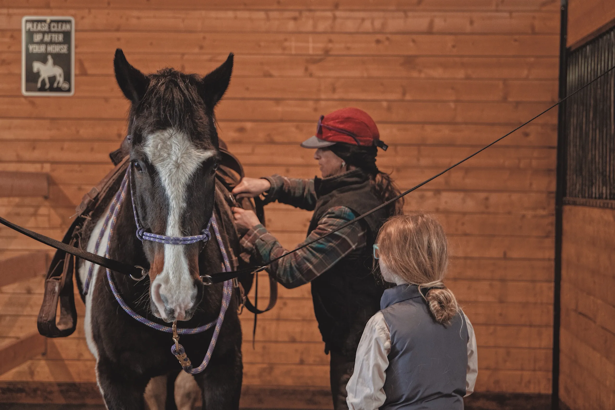 Saddling a horse in the barn aisle