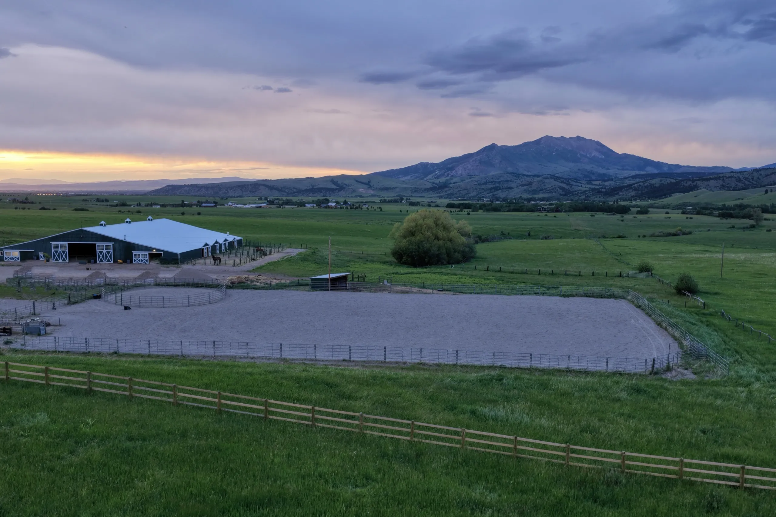 The barn and outdoor arena at sunset, peak behind