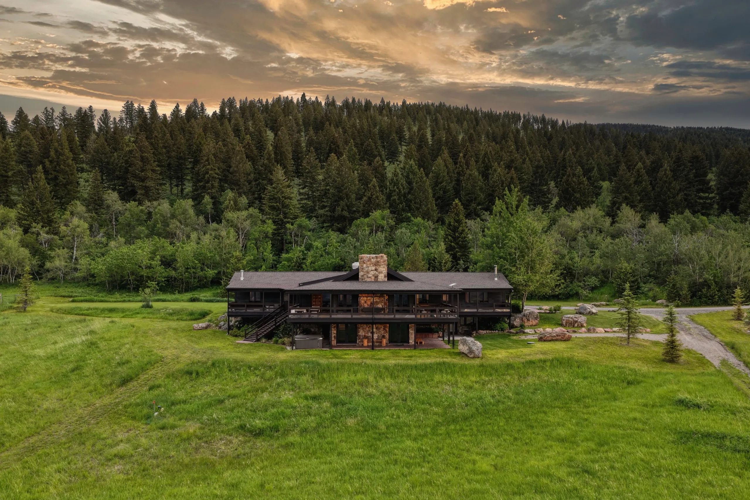 The lodge exterior from below the hill at sunset, wraparound deck against the sky